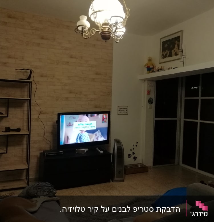 קיר לבנים עם מדף טלוויזיה ומנורה תלויה